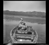 Forrest Whitaker sits in his boat on Big Bear Lake and tinkers with the motor, Big Bear Lake, 1945
