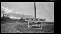 Close-up view of a sign for Santa Claus Lodge and a Coca-Cola advertisement, Gulkana, 1946