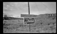Signs advertising Santa Claus Lodge and Coca-Cola posted on the roadside, Gulkana, 1946