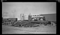 Angled view of a car and trailer sitting atop a flatbed car at the railroad yard, Anchorage, 1946