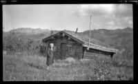 Mertie West poses in front of a log cabin, Denali National Park and Preserve vicinity, 1946