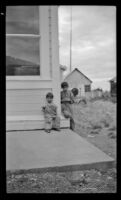 Two young Native American boys sit outside a building, Circle, 1946