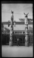 Mertie West poses between 2 totem poles, Ketchikan, 1946