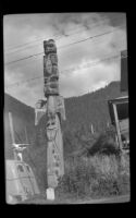 Totem pole standing along the road, Saxman, 1946