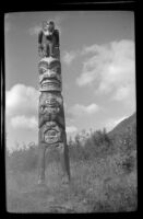 Totem pole with an arched base stands at Saxman Totem Park, Saxman, 1946