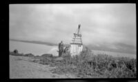 H. H. West poses next to a deteriorating beacon, Metlakatla, 1946