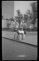 Mertie West stands with luggage on the curb outside Union Station, Los Angeles, 1946