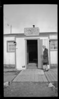 Mertie West stands outside the Shawcreek Lodge's front door, [Delta Junction vicinity?], 1946