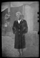 Mertie West stands near some totem poles at Saxman Totem Park, Saxman, 1946