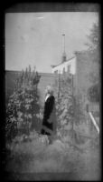 Mertie West stands in a downtown flower garden, Anchorage, 1946