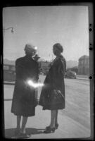 Mertie West and a fellow ship passenger stand and chat on a sidewalk, Anchorage, 1946