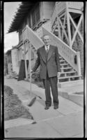 Wayne West poses with a broom behind his home, Santa Ana, 1946