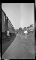 Porter standing beside a Canadian Pacific Railway train stopped at a small station en route to Vancouver, British Columbia vicinity, 1947