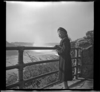 Mertie West stands at a railing and looks at the falls, Niagara Falls, 1947