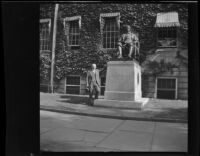 H. H. West poses beside the statue of John Harvard in Harvard Yard, Cambridge, 1947