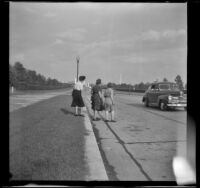 Mertie West and 2 other women cross Memorial Avenue outside the entrance of Arlington National Cemetery, Arlington, 1947