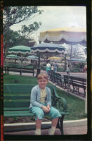 Debbie West seated on a bench at Disneyland, Anaheim, 1957