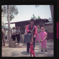 Debbie West stands beside an organ grinder and monkey at Knott's Berry Farm, Buena park, 1957