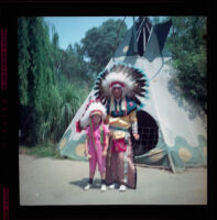 Debbie West stands beside a man dressed as an American Indian at Knott's Berry Farm, Buena Park, 1957