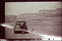 Mertie West seated on the bumper of her Buick car in Vermilion Cliffs National Monument, 1942