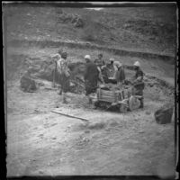 Men standing around a hole beside a wooden cart filled with earth, Turkey, 1895