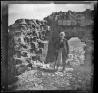 Elderly man standing in front of ruins on a hill above a town, Bursa (perhaps), Turkey, 1895