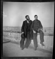 Two men seated on a low wall with a town visible in the distance, Turkey, 1895