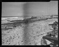 Debris and wreckage of Bill's Barge litters the seashore after a storm, Newport Beach, 1936