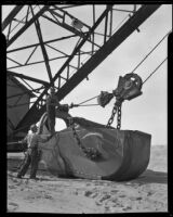 Workers connect a large sand bucket to a crane, Calexico, 1936
