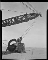 Canal construction workers attach a large sand bucket to a crane, Calexico, 1936