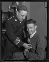 Police Chief James Davis pins a badge on to smiling teenager Jack Blaikie, Los Angeles, 1936