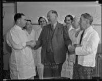 Dr. Edgar Spear and nurse Charles Whitehead shake hands with Police Detective Vern Filby at the Georgia Street Hospital, Los Angeles, 1936