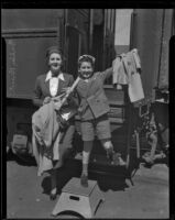 Child actor Bobby Breen and his sister and manager Sally Breen disembark from a train, 1936