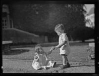 pBaby girl hands a ball to a toddler boy on graduation day at Chapman College, Orange, 1936