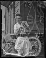 Man holds a lion cub n front of an Al G. Barnes Wild Animal Circus car, Los Angeles, 1936