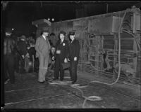 Los Angeles Railway employees, B. E. Rindell and B. Tallant, speak with a bystander beside their overturned street car, Los Angeles, 1934