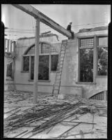 Workman sits on a support beam of the old "opera house" during its demolition, South Pasadena, 1939
