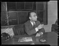 Philip Robinson sits smoking at his desk, Los Angeles, 1939