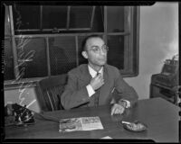 Philip Robinson, suspected of participation a rail ticket scam, sits at his desk adjusting his tie, Los Angeles, 1939