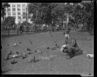 Western Union messenger, Gerry Cooke, feeds pigeons in Pershing Square, Los Angeles, 1938