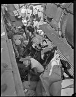 Rescuers work to remove a car wedged between 2 train cars, [between 1920-1939]