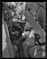 Rescuers try to access a car wedged between 2 train cars, [between 1920-1939]