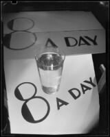 Photograph with a glass of Arrowhead water on a sign reading "8 A Day," Los Angeles, between 1935