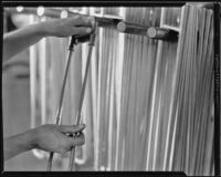 Technician holding tubing for a brass horn at the F. E. Olds and Son plant, Los Angeles, 1933-1939