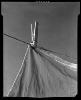 Close-up view of a clothespin holding laundry on a clothesline, between 1925-1939
