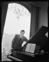 Fred Keating, actor, beside a grand piano in his Hollywood Hills house "Casa Escrow," Los Angeles, circa 1934