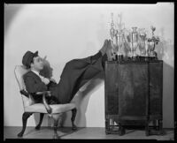 Fred Keating, actor, seated beside trophies, Los Angeles, 1934