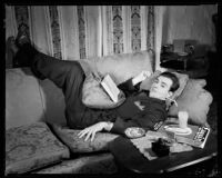 Fred Keating, actor, on a sofa in his Hollywood Hills house "Casa Escrow," Los Angeles, circa 1934