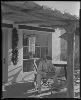 Ralph Bellamy, actor, in resort attire on the porch of a Spanish style bungalow, perhaps in Palm Springs, circa 1933