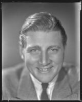 Man wearing a jacket and tie and smiling, circa 1926-1939